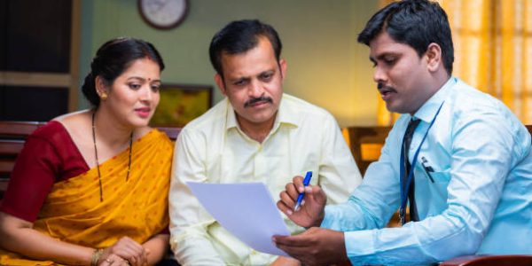 Bank officer advising about insurance policy from papers to couple at home - concept of financial support, consultant and retirement planning
